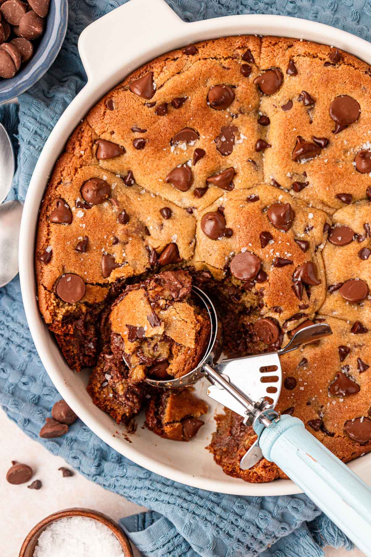 A scoop in a dish of chocolate chip cookies.