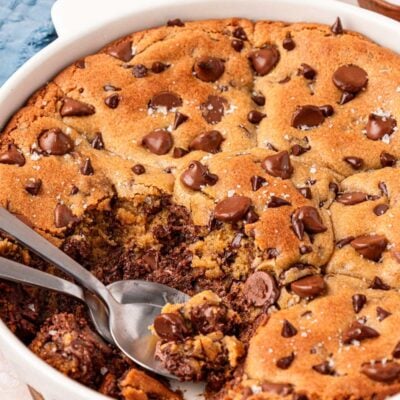 Scoopable chocolate chip cookies in a white pie dish with two serving spoons.