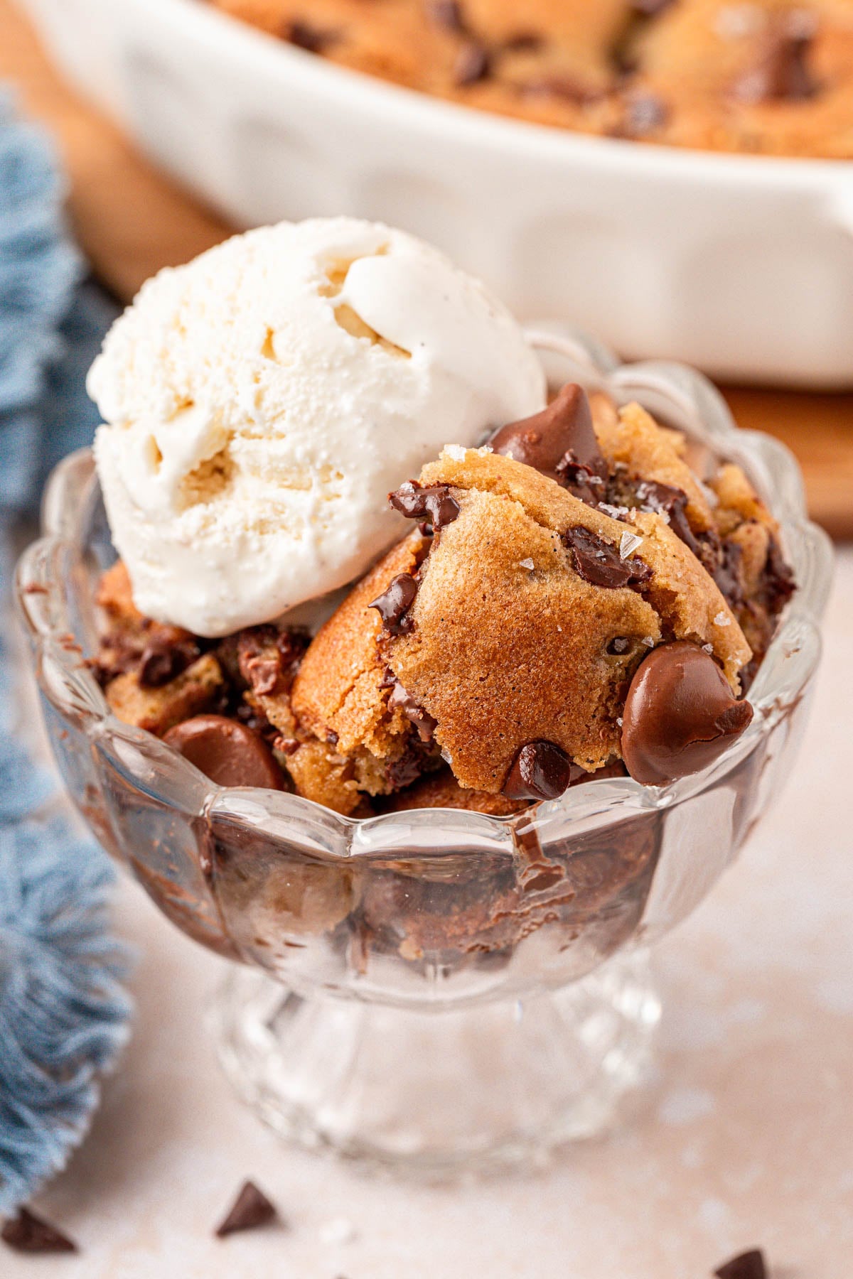 Close up of a sundae dish filled with scoopable chocolate chip cookie and vanilla ice cream.