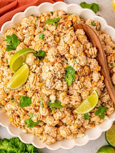 a white scalloped bowl of street corn pasta salad.