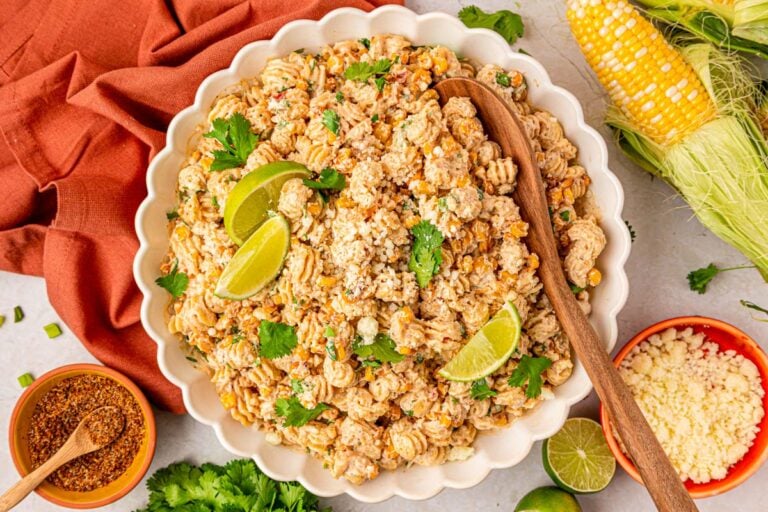 a white scalloped bowl of street corn pasta salad.