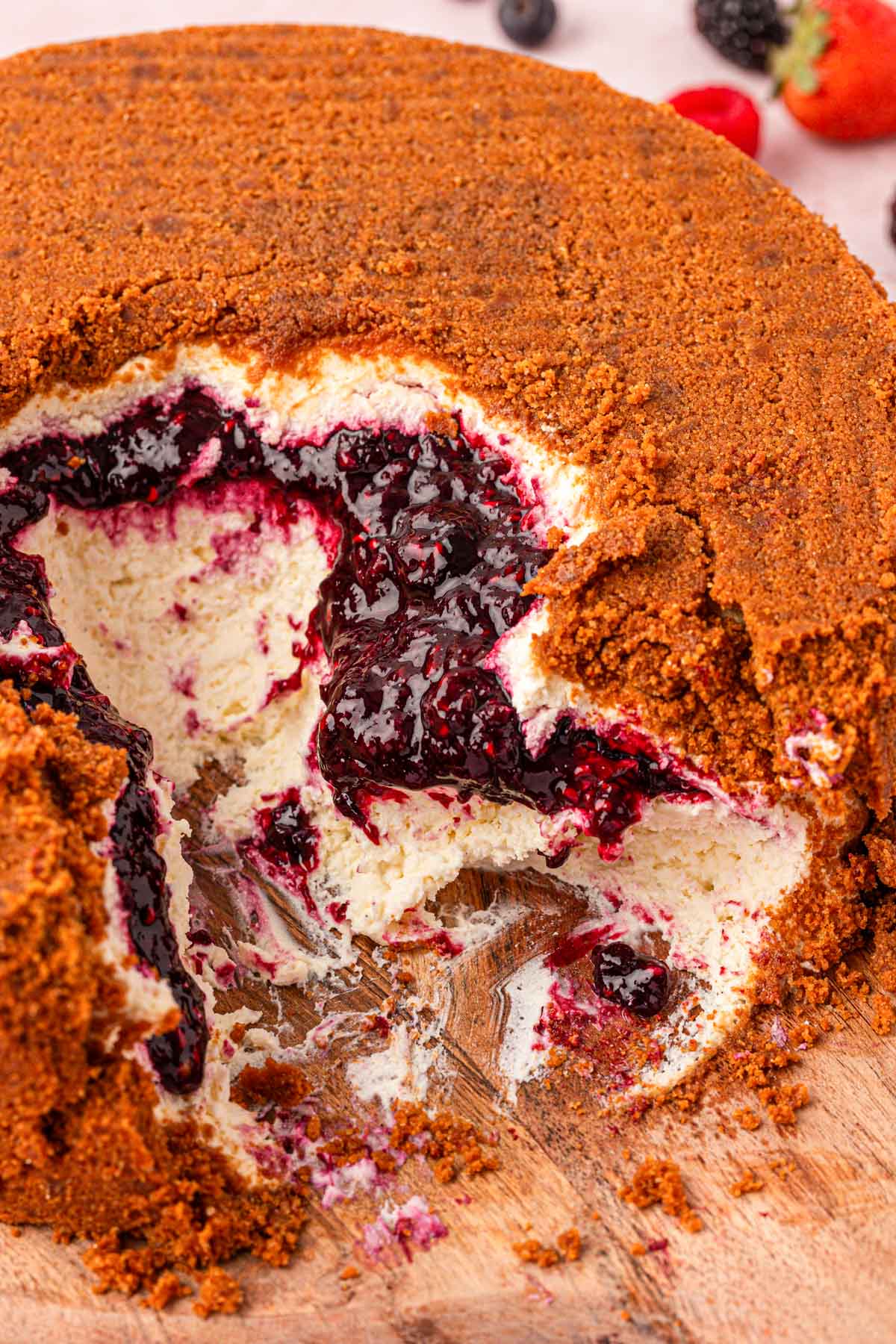 Close up of an upside down cheesecake with big scoops taken out of the middle and sides.